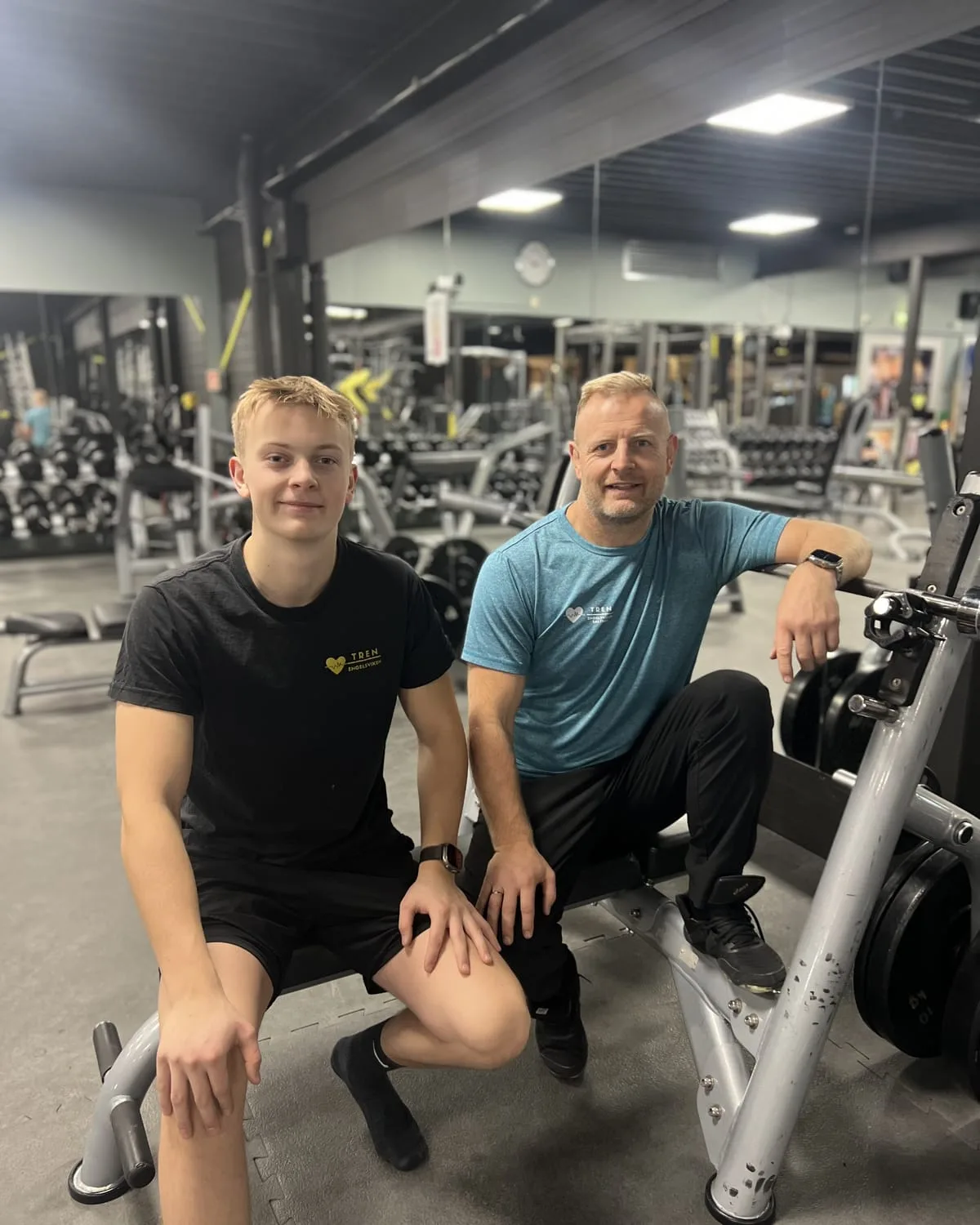 Noah og Thomas side om side i treningssalen, begge i TREN-t-skjorte